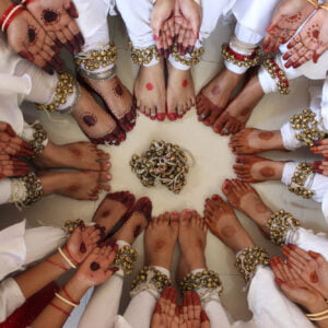 Kathak dancers in costumes and colored feet and hands sitting in a circle